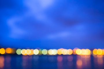 Horizon with circle bokeh lights blur at night across river
