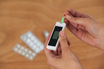 Close-up of woman hands testing blood sugar with glucometer 