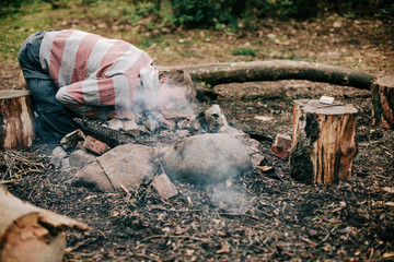 Fototapeta premium Camper blowing into campfire to get fire started.