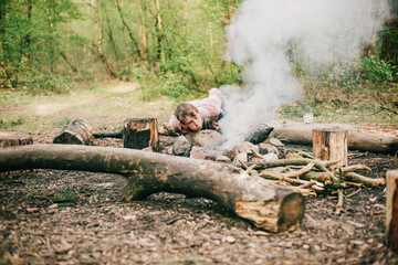 Camper blowing into campfire to get fire started.