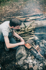 Wayfarer stirring meal in frying pan on campfire.