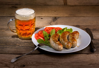 Glass of beer and sausages on the wood background