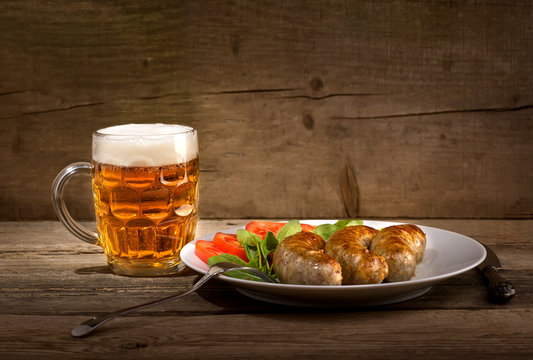 Glass of beer and sausages on the wood background