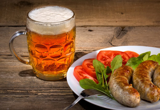 Glass of beer and sausages on the wood background