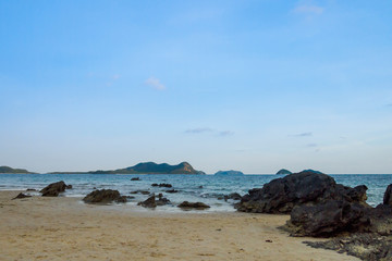 Rock on the beach with blue sky and island background