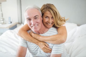 Portrait of happy senior couple embracing each other on bed