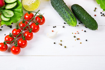 Cucumbers, radish, tomatoes cherry, olive oil, herb and spices on old white wooden background. Set for healthy foods. Ingredients for salad.