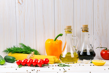 Spaghetti, tomatoes cherry, olive oil, herb and spices on old white wooden background. Set for healthy foods. Ingredients for salad.