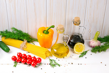 Spaghetti, tomatoes cherry, olive oil, herb and spices on old white wooden background. Set for healthy foods. Ingredients for salad.