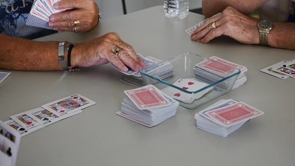 Close up of senior citizens playing a game of cards - Powered by Adobe