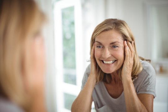 Smiling senior woman looking at mirror