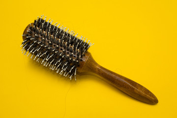 The problem of baldness, dropped hair on the comb on a yellow background.