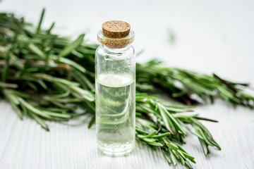 natural cosmetic oil with fresh rosemary on light wooden table background