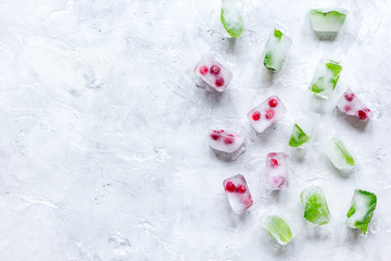 Ice cubes with berries and mint stone background top view mock up