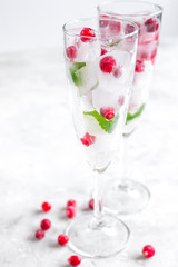 Ice cubes with berries and mint in glasses for summer drink white background