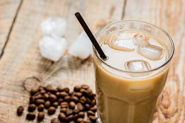 coffee break with cold iced latte and beans on wooden table background
