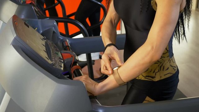 Woman checking heart rate on smartwatch during fitness exercise on treadmill