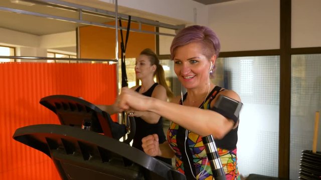 Woman checking heart rate monitor app on the smartphone while doing arm punching exercises on the stepper