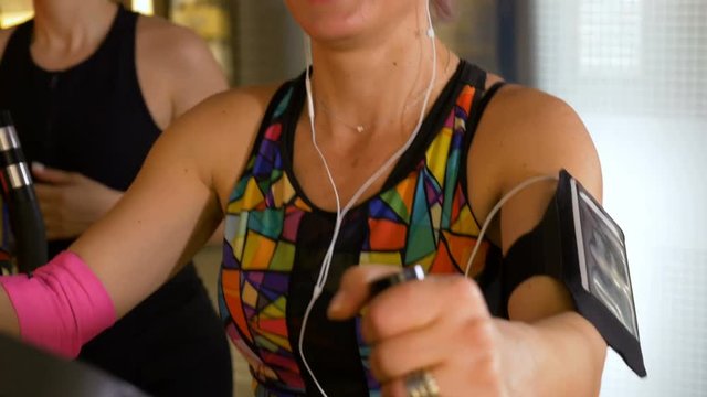 Fitness trainer with headphones and tracker gadget working out on the stepper