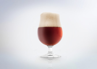 Glass of a belgian amber ale beer with foam. Isolated on white background.