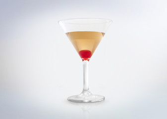 Glass of a gold / yellow / amber cocktail drink with a red cherry on the bottom. Isolated on white background. 