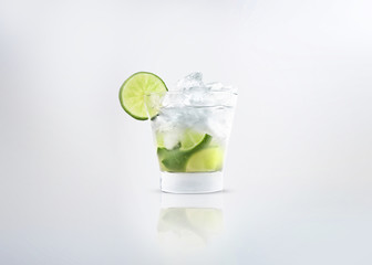 A glass of a alcoholic cocktail drink of caipirinha or mojito with fresh lemon on the glass and...