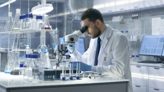 Research Scientist Looks into Microscope and Writes Down Observations. He's Conducts Experiments with His Colleagues in Modern Laboratory. Shot on RED EPIC-W 8K Helium Cinema Camera.