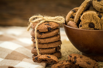 Close up stacked chocolate chip cookies on  napkin with wooden background