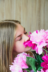 Portrait of a young beautiful blonde caucasian young woman keeps bouquet pink and red peonies flowers