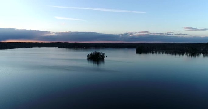 Lake bodom, Cinema 4k aerial flight towards a little island, on mirroring bodom lake, on a sunny spring evening, in Espoo, Finland