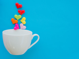 White cup with colorful of heart on Valentine's Day love concept on blue sky background