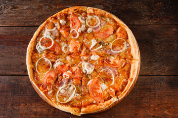 Junk food, unhealthy eating, bad habits, calories. Hot fresh baked pizza with ham, onion, tomato and cheese served on dark wooden table, flat lay.
