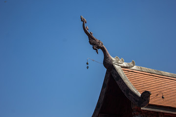 Fototapeta na wymiar Thai temple roof top with blue sky background