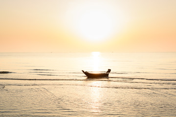 Silhouette of fishing boat and Beautiful tropical sunrise on the beach.