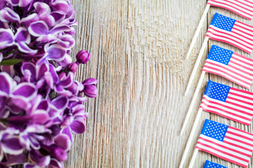 Fresh spring purple lilac and miniature flags focused on wooden board with room for copy