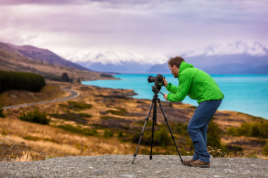 Travel photographer taking nature landscape pictures in New Zealand at sunset. Man shooting at Peter's lookout, famous tourist attraction at Pukaki Lake.