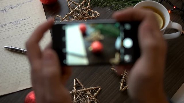 Man hands taking the photo on smart phone of christmas decoration on brown wood background.