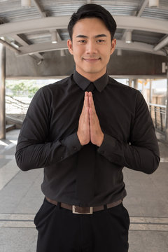 friendly businessman greeting in asian gesture, sawasdee or namaste