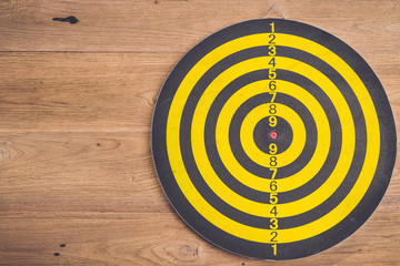 Dart arrow and dartboard on brown wooden background. Composition white free space for text or design