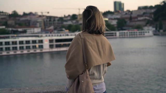 Pensive, young woman admire boat floating on river in the evening

