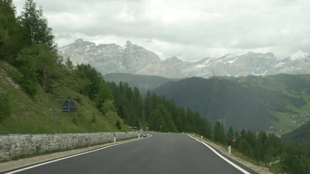 Driving POV entering Alta Badia near Corvara, Northern Italy. Prominent Dolomites peaks include La Varella and Cunturines, in the Cunturines subgroup of the Fanes Group.
