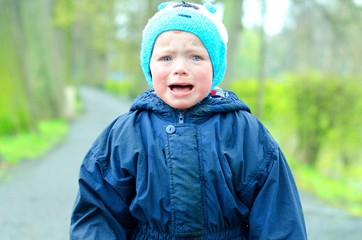 Angry toddler in a park. Boy stopped walking and doesn´t want to continue. Child afraids of being abandoned. Raising children concept.