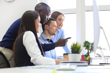 Team of colleagues brainstorming together while working on the computer.