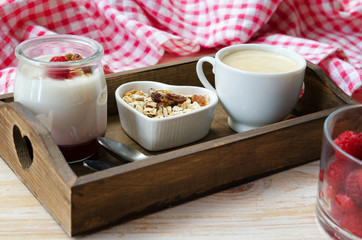 Wooden tray with fruit on the bottom yogurt jar, muesli  and cup of coffee. Healthy  breakfast..