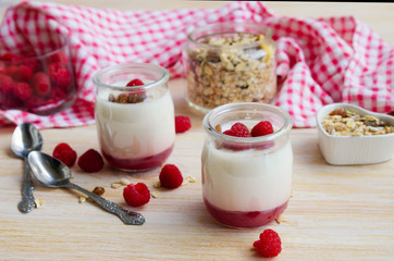 Fruit on the bottom yogurt jars, oatmeal  muesli and fresh raspberry on wooden table. Yoghurt with fruit jam background. Concept for heathy eating or breakfast.
