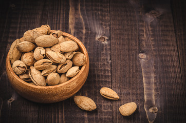 almonds in a bowl on dark background/almonds in a wooden plate dark background