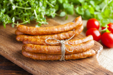 Raw sausage, tomato and fresh herbs on wooden and canvas background