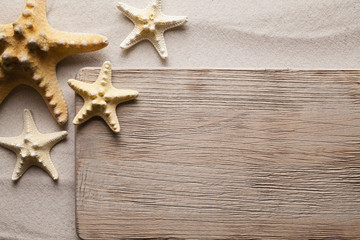 Fototapeta na wymiar Starfish and wooden board on beach sand