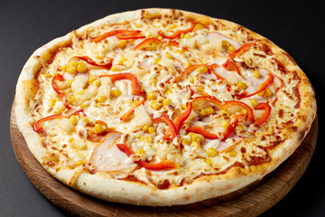 Hot pizza Hawaii on a rustic wooden table.