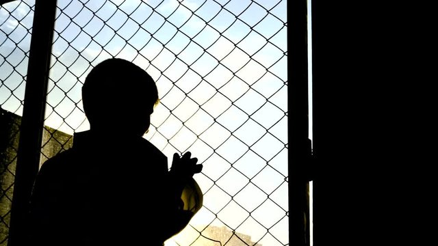 Orphans in slums looking on the sun through the lattice fence 4K